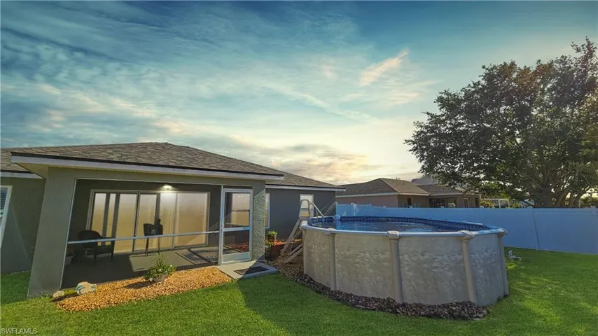 Rear view of property with a fenced in pool, fence, stucco siding, a lawn, and a sunroom