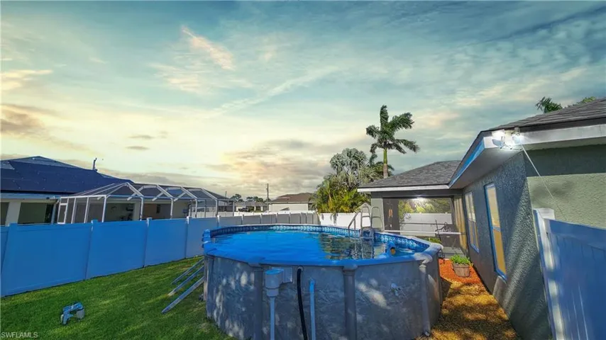 Pool at dusk with a fenced backyard, a fenced in pool, and a lawn