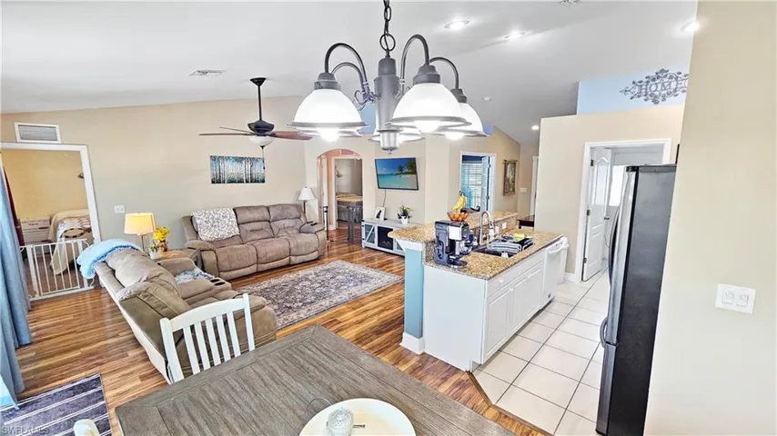 Kitchen featuring visible vents, lofted ceiling, arched walkways, freestanding refrigerator, and a sink