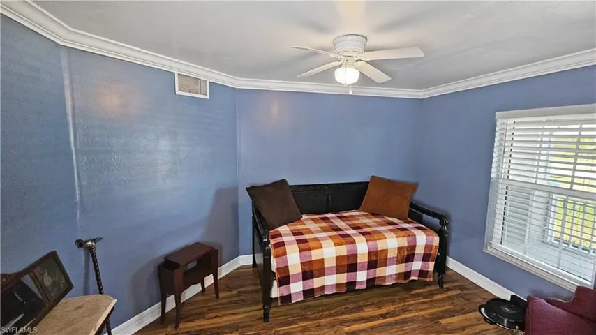 Bedroom featuring visible vents, ornamental molding, baseboards, and wood finished floors