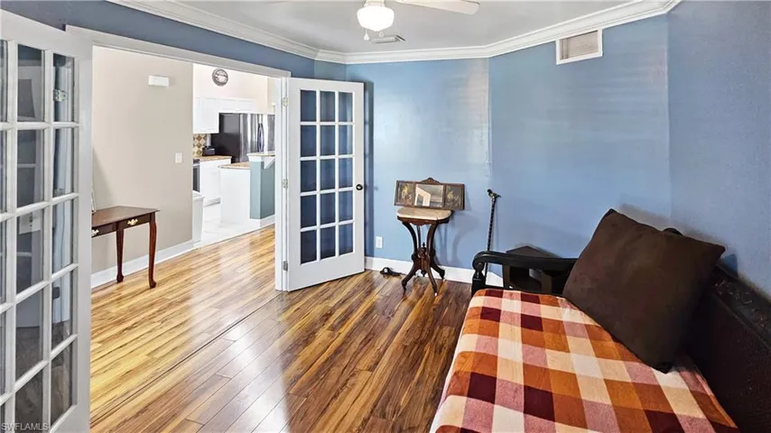 Living area with visible vents, independent washer and dryer, french doors, wood-type flooring, and crown molding