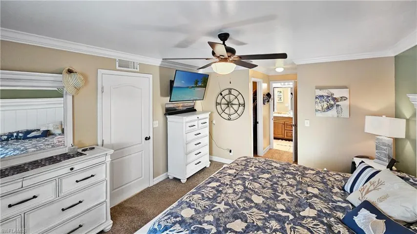 Bedroom featuring visible vents, crown molding, baseboards, and dark colored carpet
