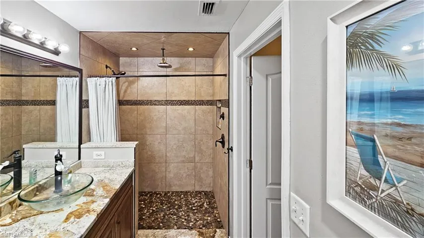 Full bath featuring a tile shower, visible vents, and vanity