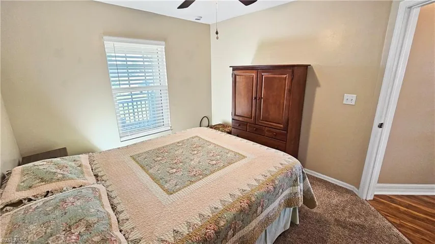 Bedroom with baseboards, dark wood-type flooring, and a ceiling fan