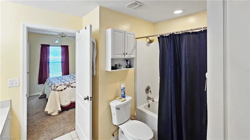 Ensuite bathroom with visible vents, shower / tub combo with curtain, toilet, ensuite bathroom, and a ceiling fan