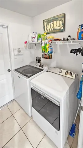 Clothes washing area with washer and dryer, light tile patterned flooring, and laundry area