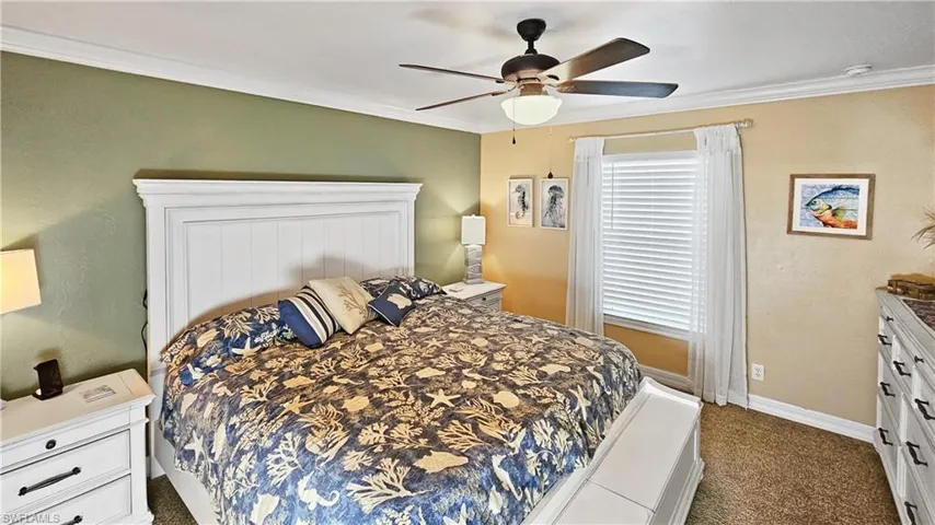 Bedroom featuring dark carpet, a ceiling fan, crown molding, and baseboards