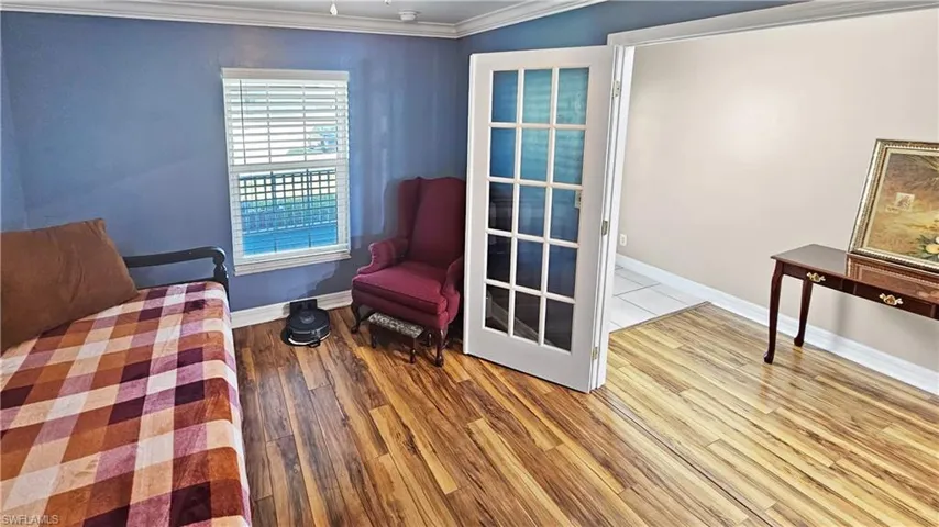 Living area with wood finished floors, baseboards, and ornamental molding