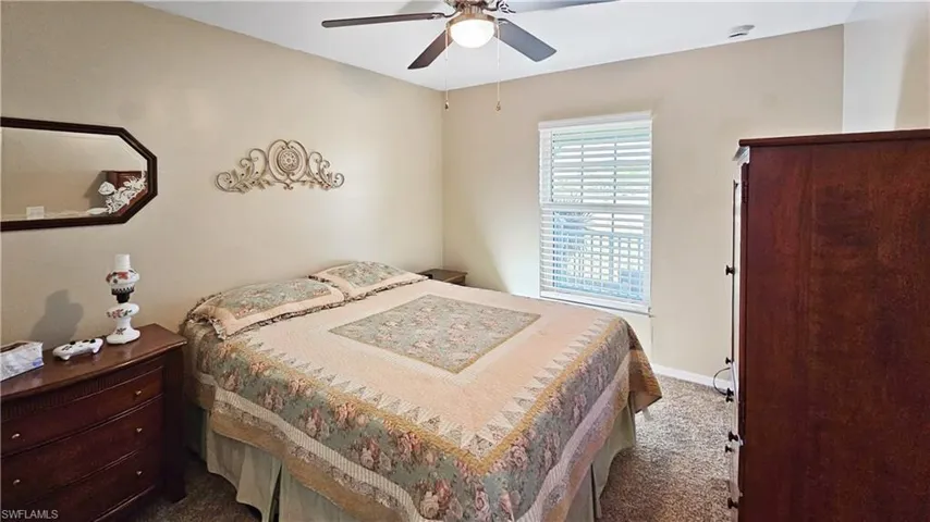 Bedroom with baseboards, dark colored carpet, and ceiling fan