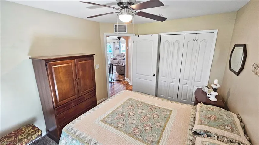 Bedroom with wood finished floors, visible vents, a closet, and ceiling fan
