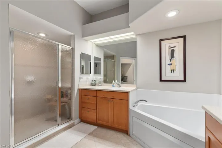 Full bath featuring vanity, a garden tub, a shower stall, light tile patterned flooring, and recessed lighting