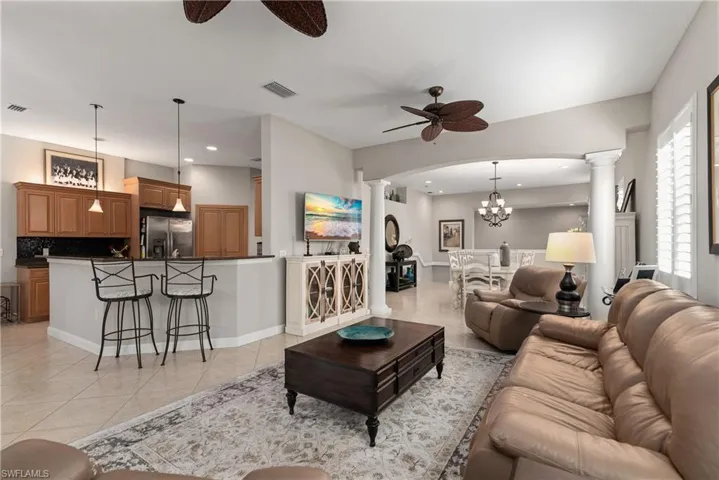 Living area with decorative columns, a chandelier, light tile patterned flooring, a ceiling fan, and recessed lighting
