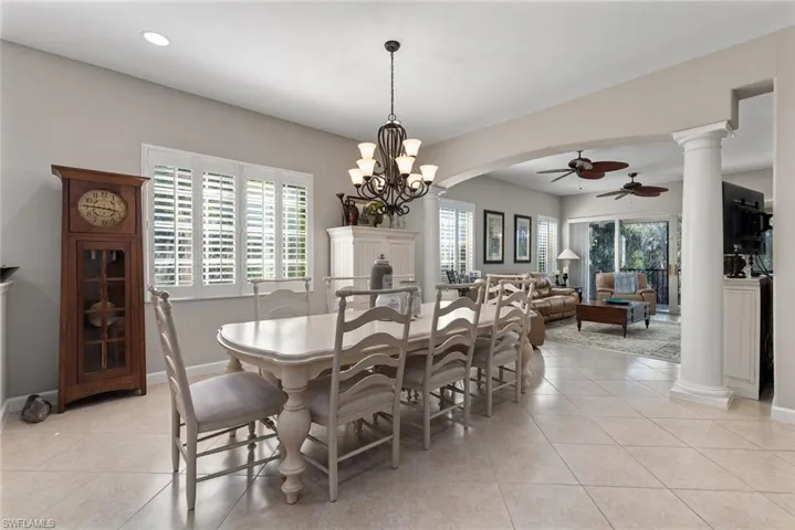 Dining space with ornate columns, a ceiling fan, light tile patterned floors, and healthy amount of natural light