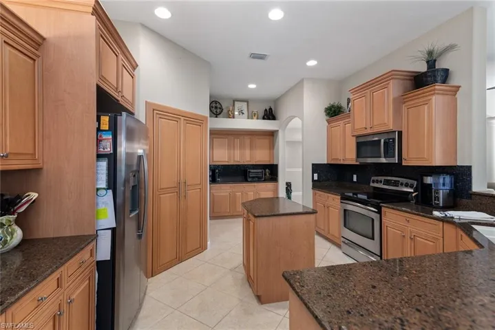 Kitchen featuring appliances with stainless steel finishes, tasteful backsplash, a kitchen island, light tile patterned floors, and recessed lighting