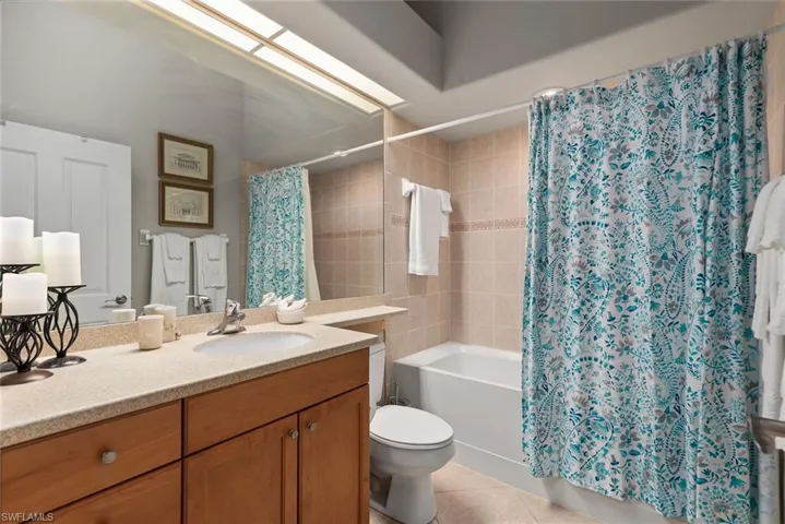Full bathroom with vanity, shower / bath combo, and light tile patterned floors