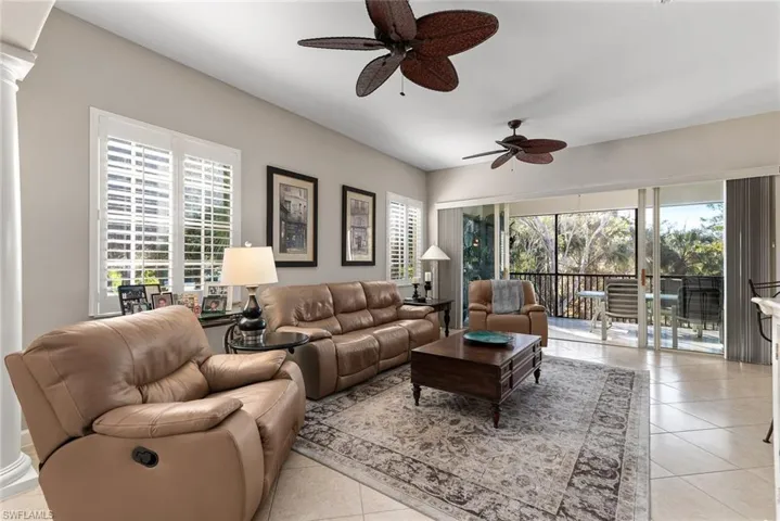 Living area featuring light tile patterned floors, a ceiling fan, and decorative columns