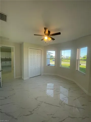 Unfurnished living room with sink, light tile patterned floors, a raised ceiling, and ceiling fan