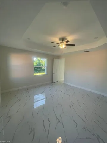 Kitchen with white cabinets, sink, a center island with sink, a raised ceiling, and light tile patterned floors