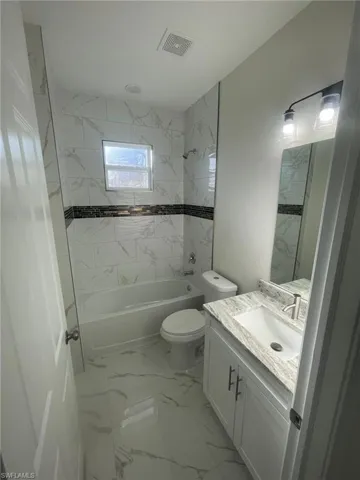 Bathroom with tile patterned flooring, tile walls, and separate shower and tub