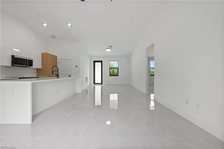 Kitchen with stainless steel microwave, modern cabinets, a sink, white cabinets, and baseboards
