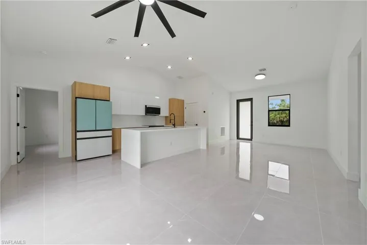 Unfurnished living room with a ceiling fan, a sink, light tile patterned floors, baseboards, and recessed lighting