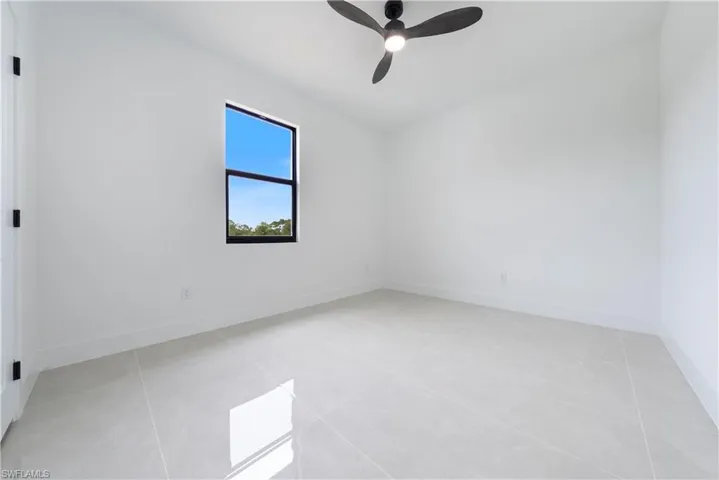 Spare room featuring a ceiling fan, light tile patterned floors, and baseboards