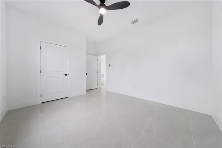 Spare room with ceiling fan, baseboards, and light tile patterned floors