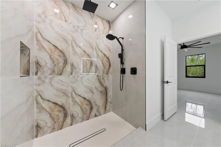 Full bathroom with a marble finish shower, baseboards, and ceiling fan