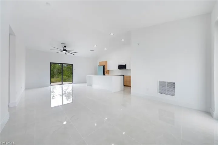 Unfurnished living room with a ceiling fan, vaulted ceiling, baseboards, light tile patterned floors, and recessed lighting