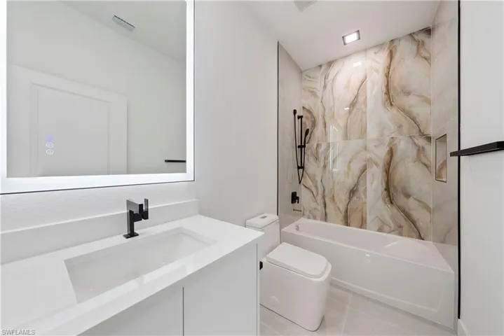 Bathroom with toilet, vanity, bathtub / shower combination, and tile patterned floors