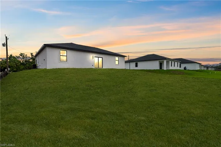 Rear view of property with a yard and stucco siding