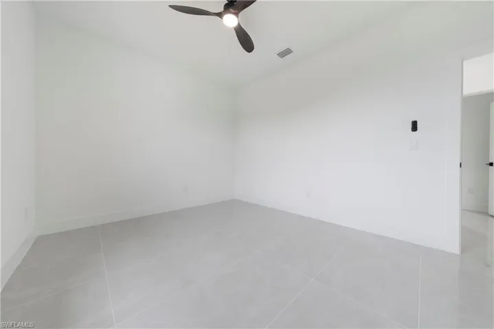 Spare room featuring ceiling fan, light tile patterned flooring, and baseboards