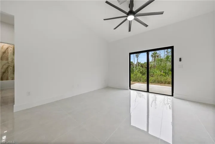 Empty room featuring lofted ceiling, a ceiling fan, light tile patterned flooring, and baseboards