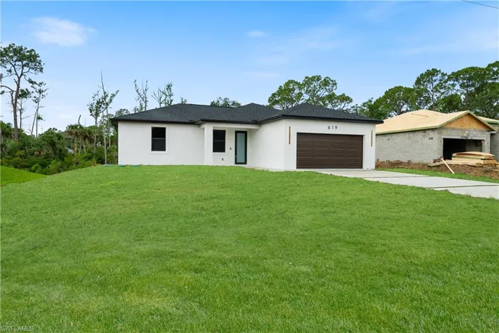 Prairie-style house featuring stucco siding, a garage, a front lawn, and concrete driveway