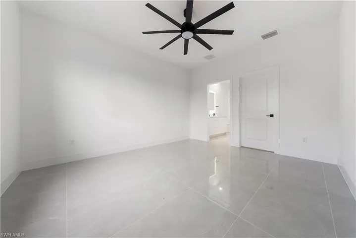 Tiled spare room featuring ceiling fan and baseboards