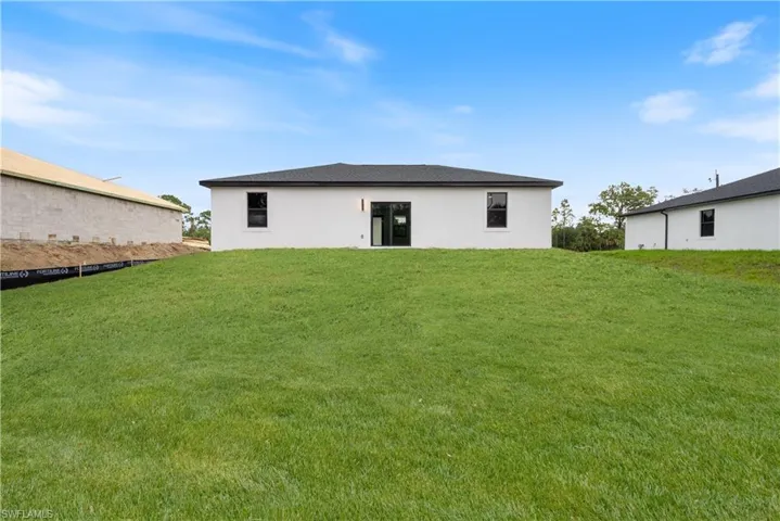 Rear view of property featuring a yard and stucco siding