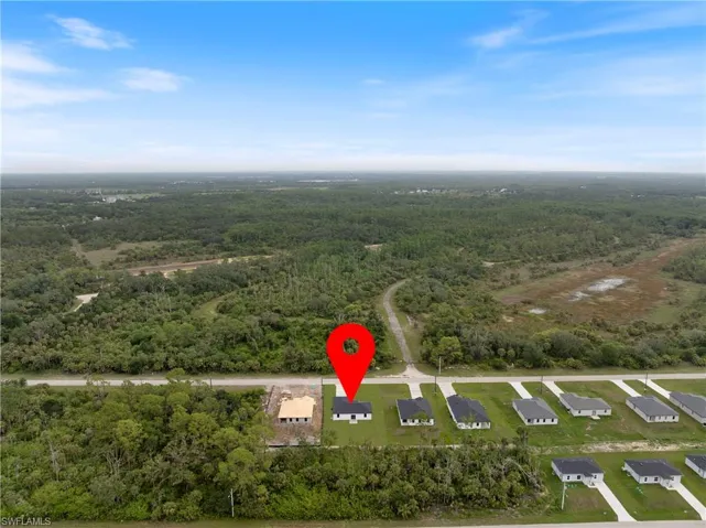 Aerial view of property and surrounding area with a heavily wooded area