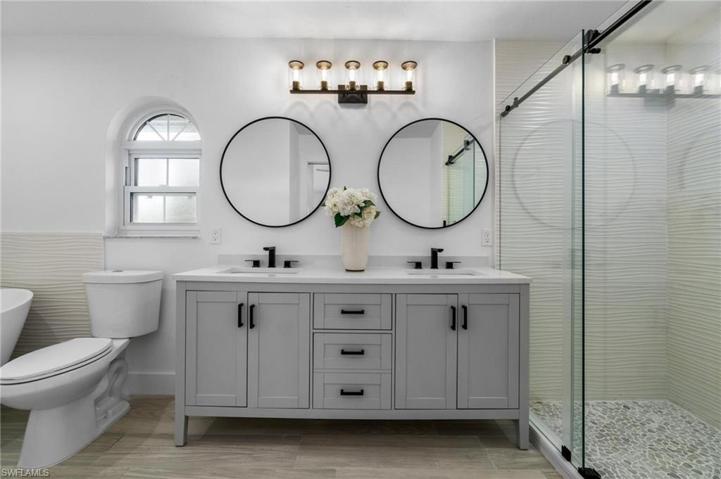 primary bathroom with dual sinks and view of newly remodeled shower with frameless shower enclosure