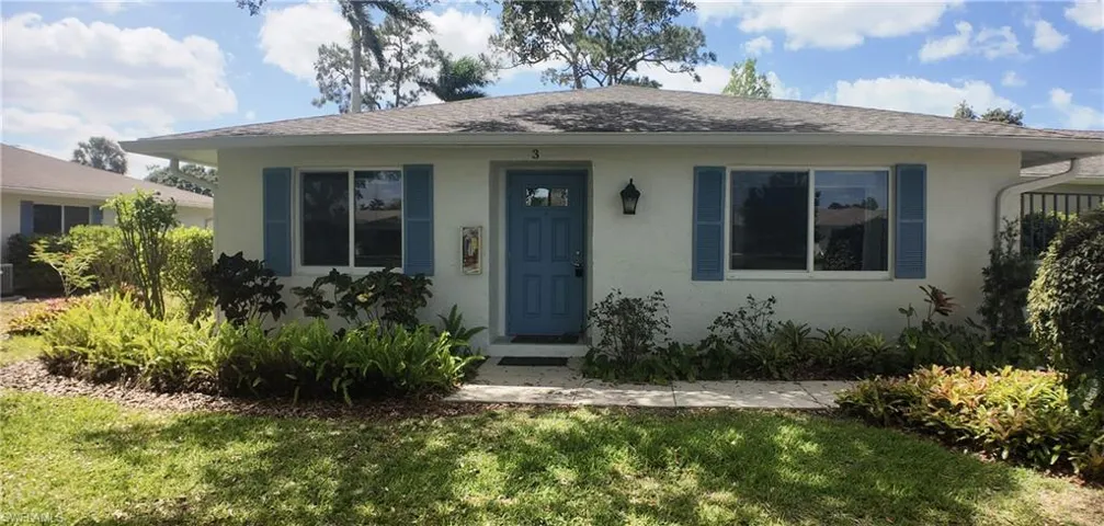 Single-story residence featuring a blue entry door, complementary window shutters, and a well-maintained front lawn