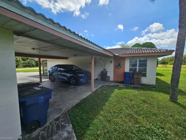 View of side of home featuring a tile roof, a yard, stucco siding, and an attached carport