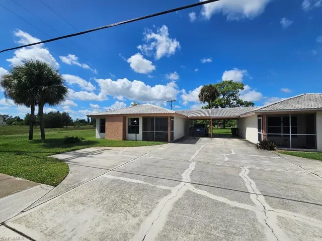 Ranch-style house with concrete driveway, stucco siding, a tiled roof, and a front yard