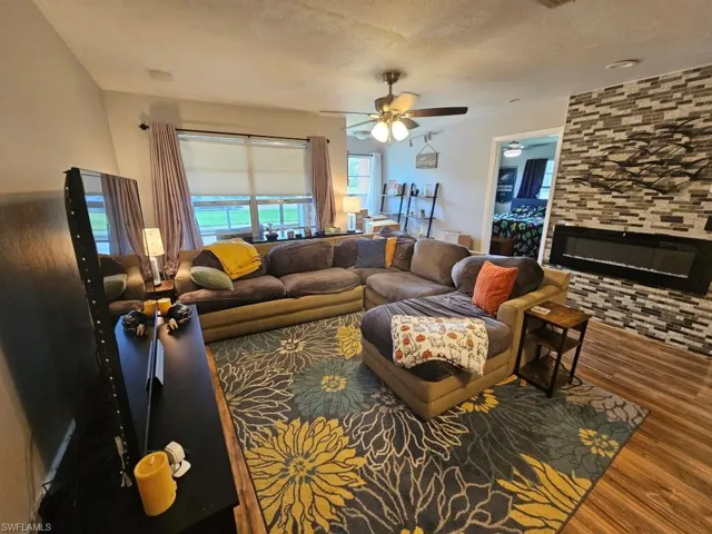 Living room featuring wood finished floors, a large fireplace, and a textured ceiling