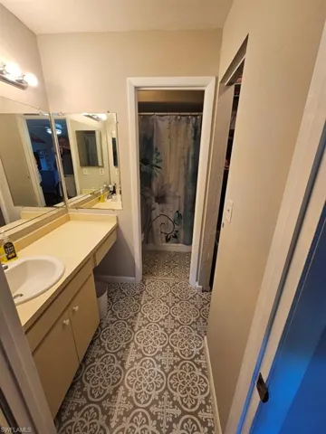 Bathroom with vanity, light tile patterned flooring, and a shower with shower curtain