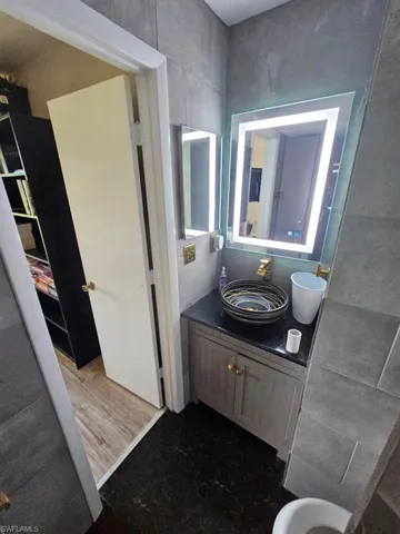 Bathroom with vanity, dark wood-type flooring, and tile walls