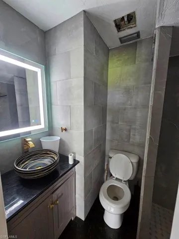 Bathroom featuring tile walls, vanity, and walk in shower