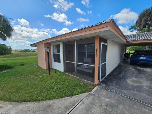 View of home's exterior with stucco siding, a lawn, an attached carport, and driveway