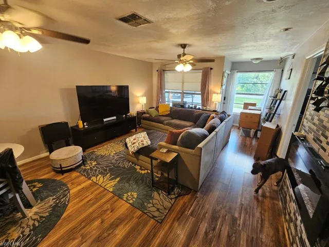 Living room with dark wood-style flooring, ceiling fan, and a textured ceiling