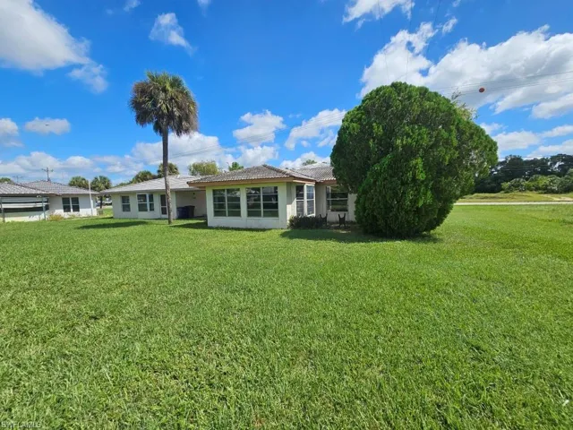 Back of house with a yard, stucco siding, and a tile roof