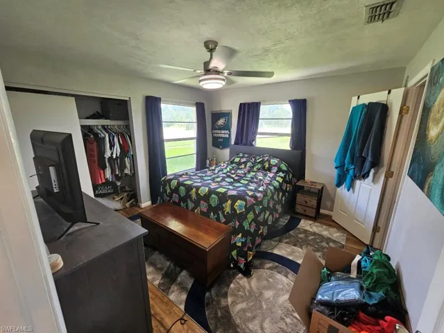 Bedroom with wood finished floors, a closet, a ceiling fan, and a textured ceiling