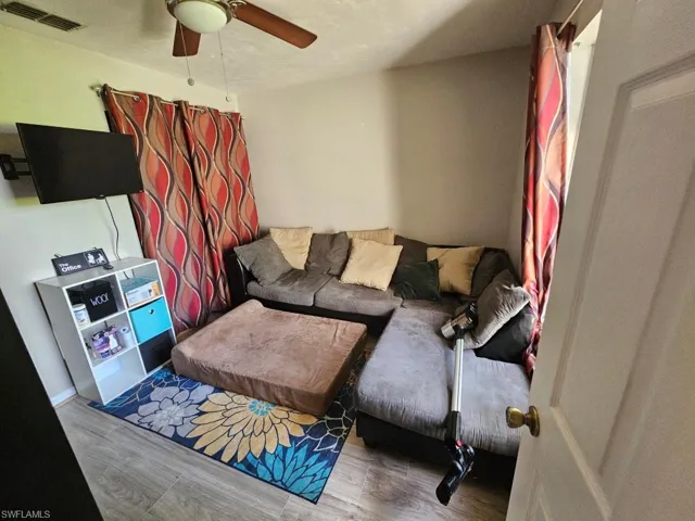 Living room featuring wood finished floors, a textured ceiling, and a ceiling fan